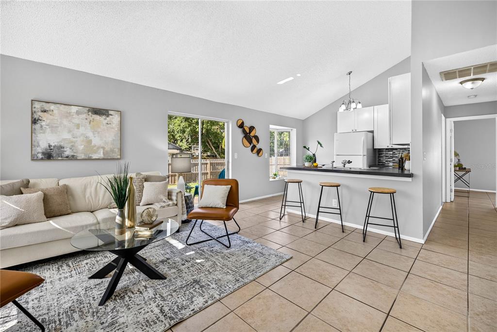 A living room with tile floors, a white sofa, and a kitchen breakfast bar — 3610 SAMMY COURT, PALM HARBOR, FL