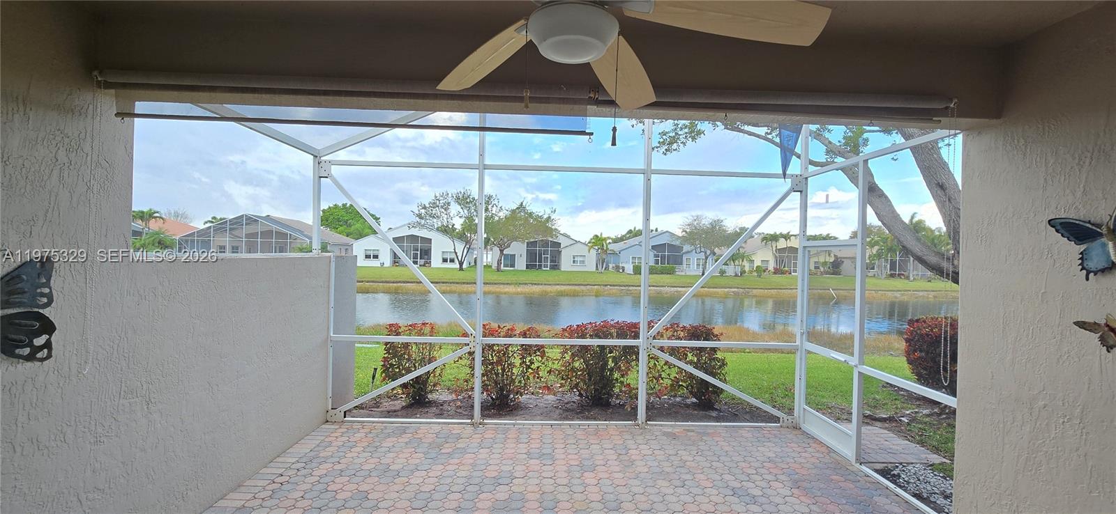 A screened-in patio overlooks a lake with neighboring houses in the background — 8214 Bellafiore Way, Boynton Beach FL 33472, BOYNTON BEACH, FL