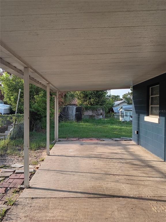A concrete carport with a white metal roof attached to a blue-sided house — 2010 PINE AVENUE, HAINES CITY, FL