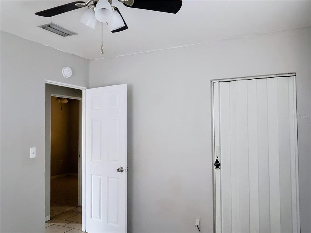 A room with light gray walls, a ceiling fan, a standard door, and a folding closet door — 2010 PINE AVENUE, HAINES CITY, FL