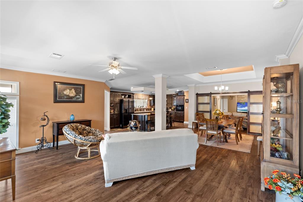 An open-concept living and dining area features wood-look flooring, a white sofa, and dark cabinetry — 2715 9TH AVENUE N, ST PETERSBURG, FL