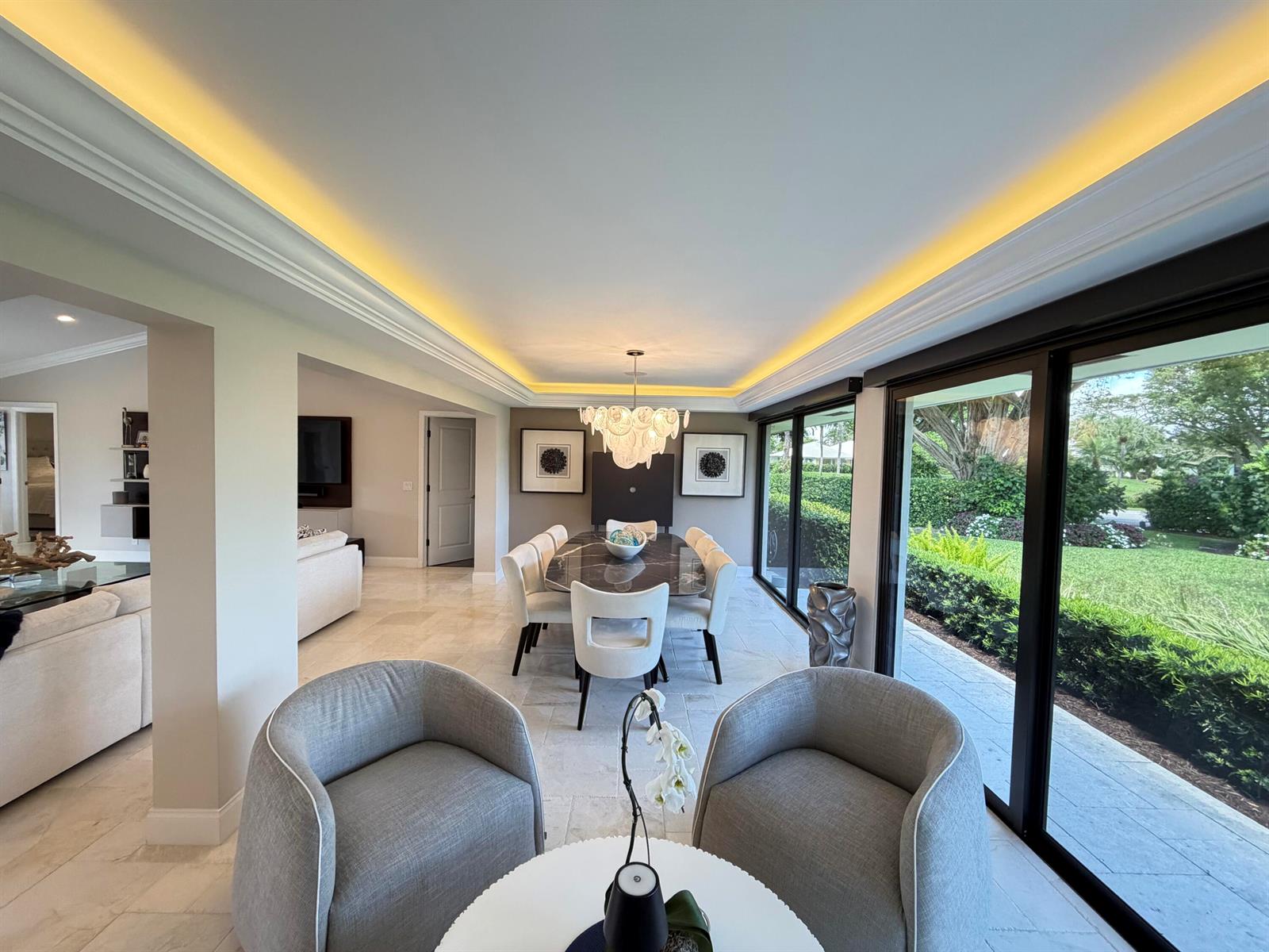 A dining room with a marble table, chandelier, and sliding glass doors overlooking a garden — 3661 Royal Tern Circle, Boynton Beach FL 33436, BOYNTON BEACH, FL