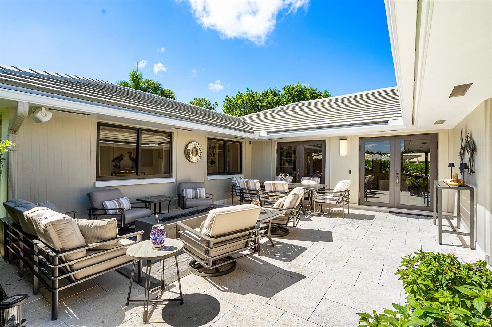 A spacious outdoor patio features a fire pit, lounge seating, and light-colored stone pavers — 3661 Royal Tern Circle, Boynton Beach FL 33436, BOYNTON BEACH, FL