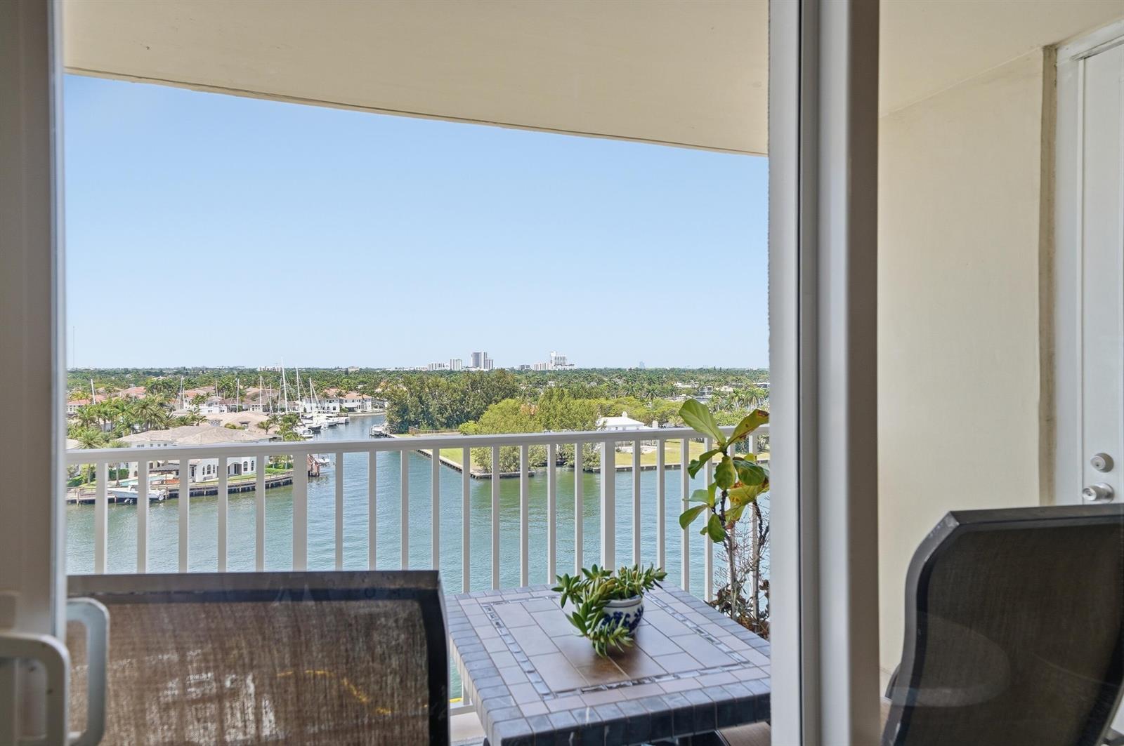 A balcony with patio furniture overlooks a canal and a distant city skyline — 1401 S Ocean Drive, Hollywood FL 33019, HOLLYWOOD, FL