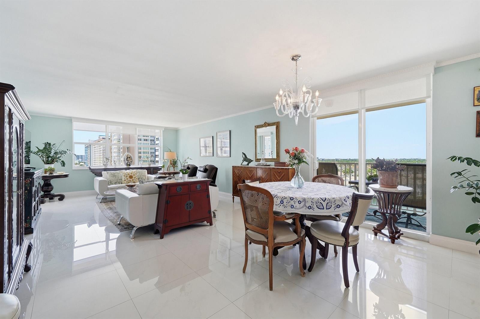 A bright living and dining area with light blue walls, white tile floors, and balcony access — 1401 S Ocean Drive, Hollywood FL 33019, HOLLYWOOD, FL