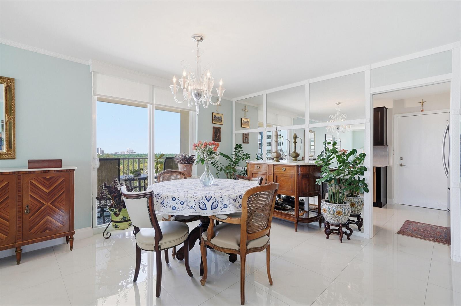 A dining room with a round table, chandelier, mirrored wall, and tile flooring — 1401 S Ocean Drive, Hollywood FL 33019, HOLLYWOOD, FL