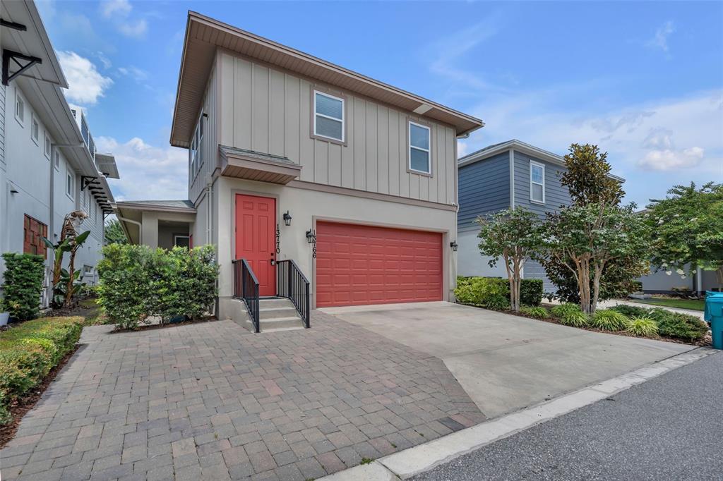 A two-story house with a red front door, a garage, and a paved driveway — 13770 ROSBASH ALLEY, ORLANDO, FL