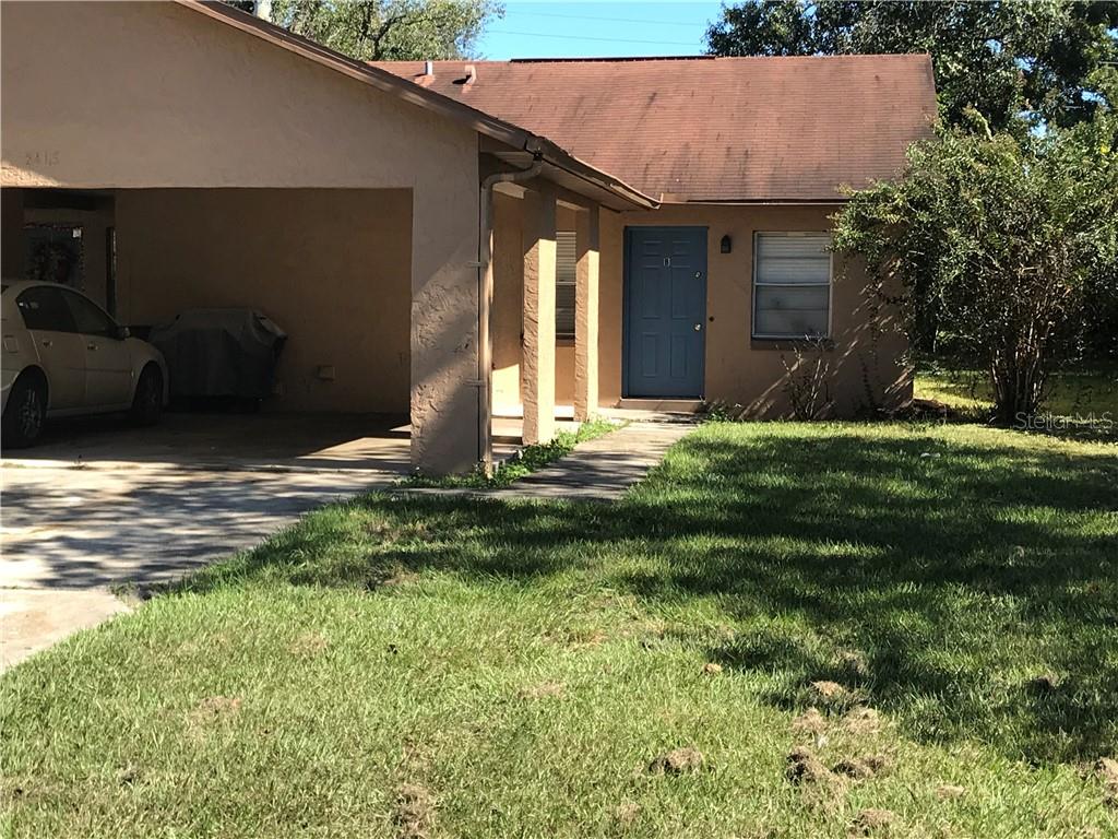A single-story house features a tan stucco exterior, a carport, and a blue front door — 2415 S CEDAR AVENUE UNIT B, SANFORD, FL
