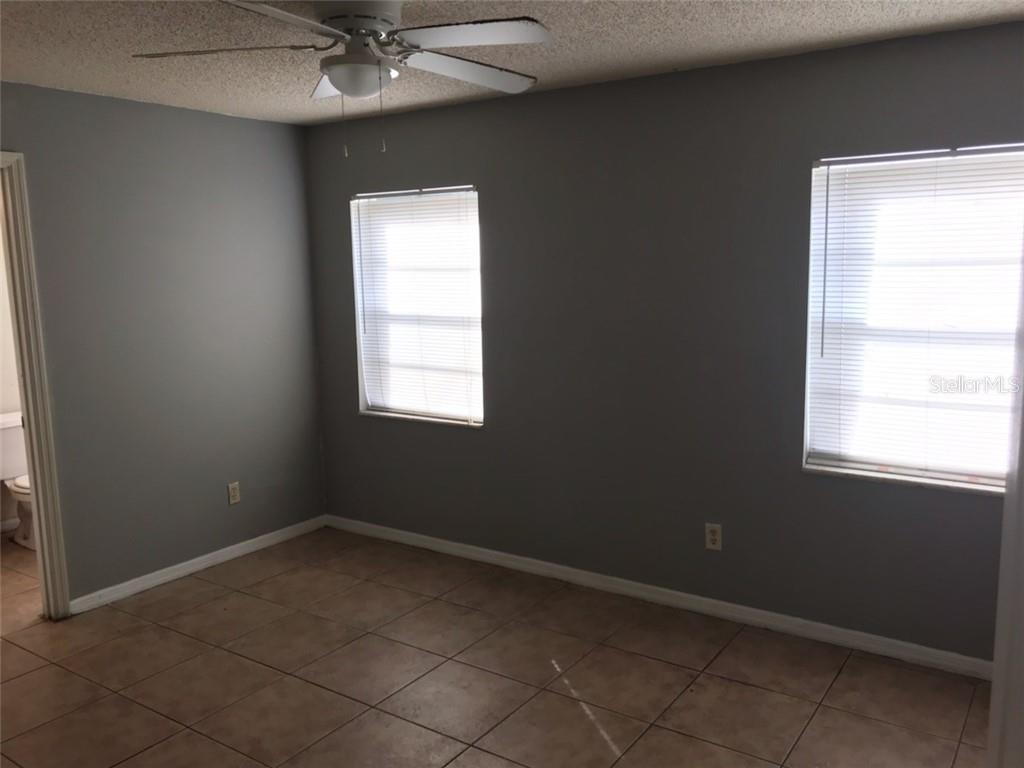An empty bedroom with gray walls, tile flooring, two windows, and a ceiling fan — 2415 S CEDAR AVENUE UNIT B, SANFORD, FL