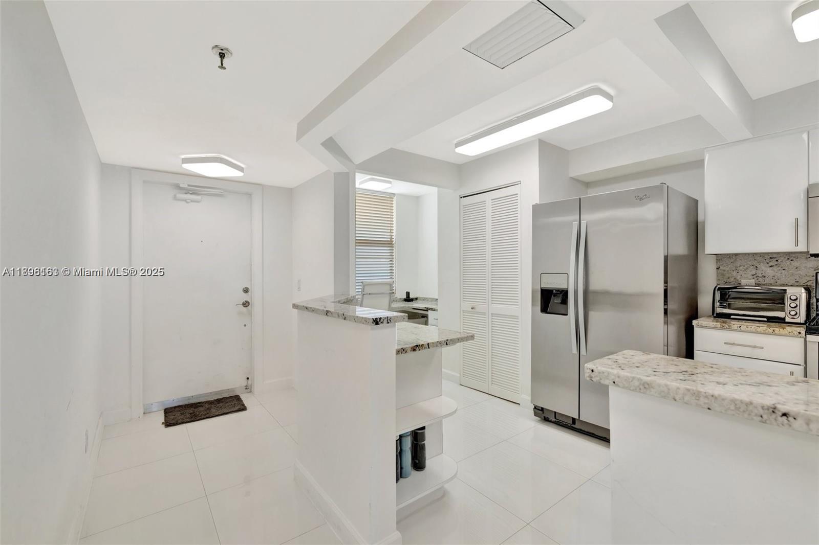 A kitchen features white cabinets, granite countertops, stainless steel appliances, and white tile flooring — 9650 S Ocean Dr # 2003, Jensen Beach FL 34957, JENSEN BEACH, FL