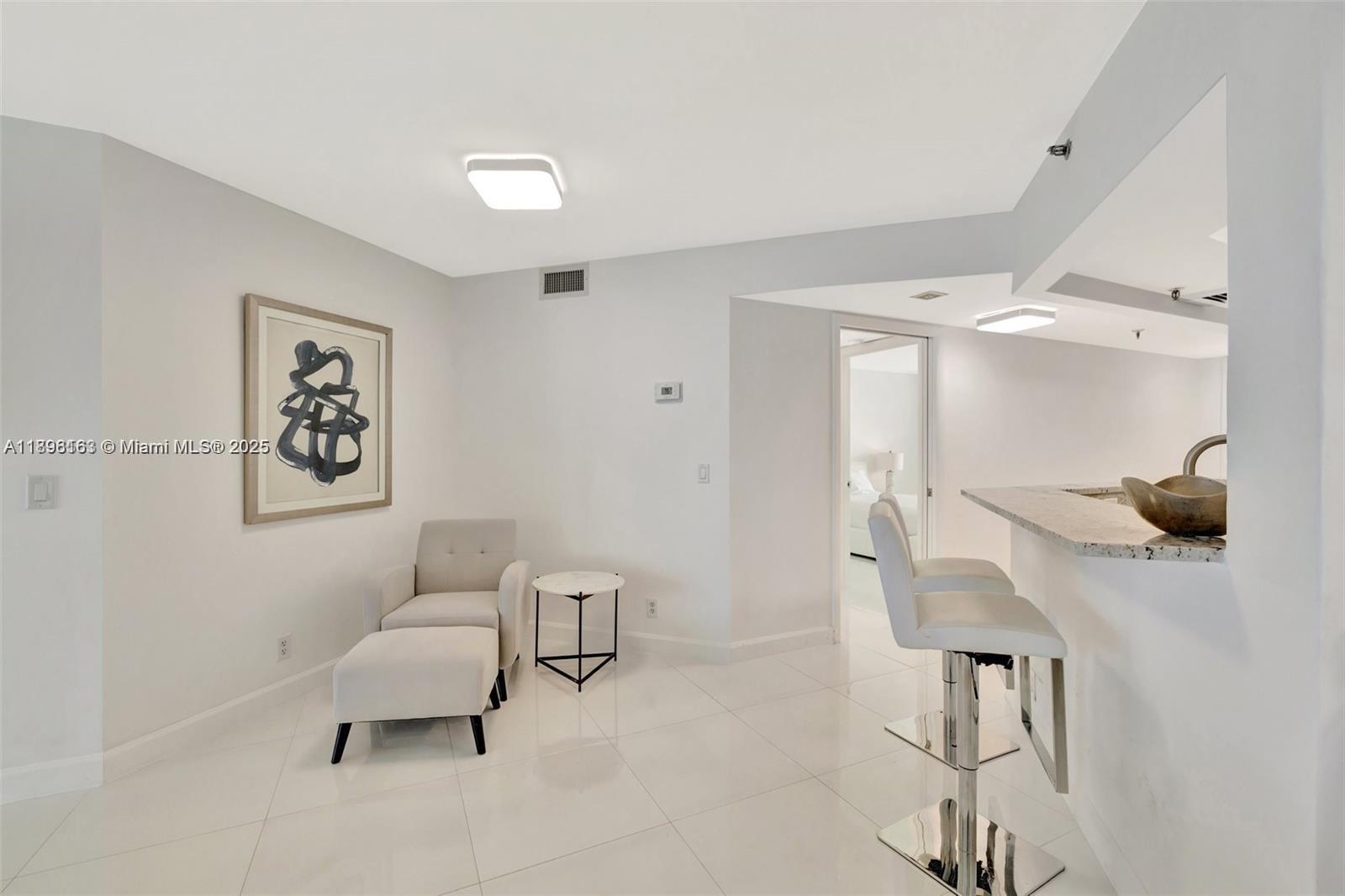 A bright room features white tile floors, a small seating area, and a breakfast bar — 9650 S Ocean Dr # 2003, Jensen Beach FL 34957, JENSEN BEACH, FL
