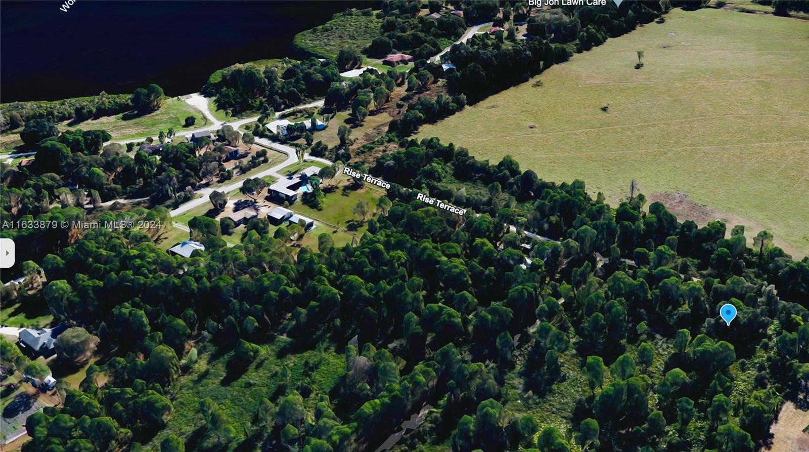 This aerial view shows a residential area with houses, dense trees, and a nearby lake — 6349 rise terrace, Sebring FL 33875, SEBRING, FL