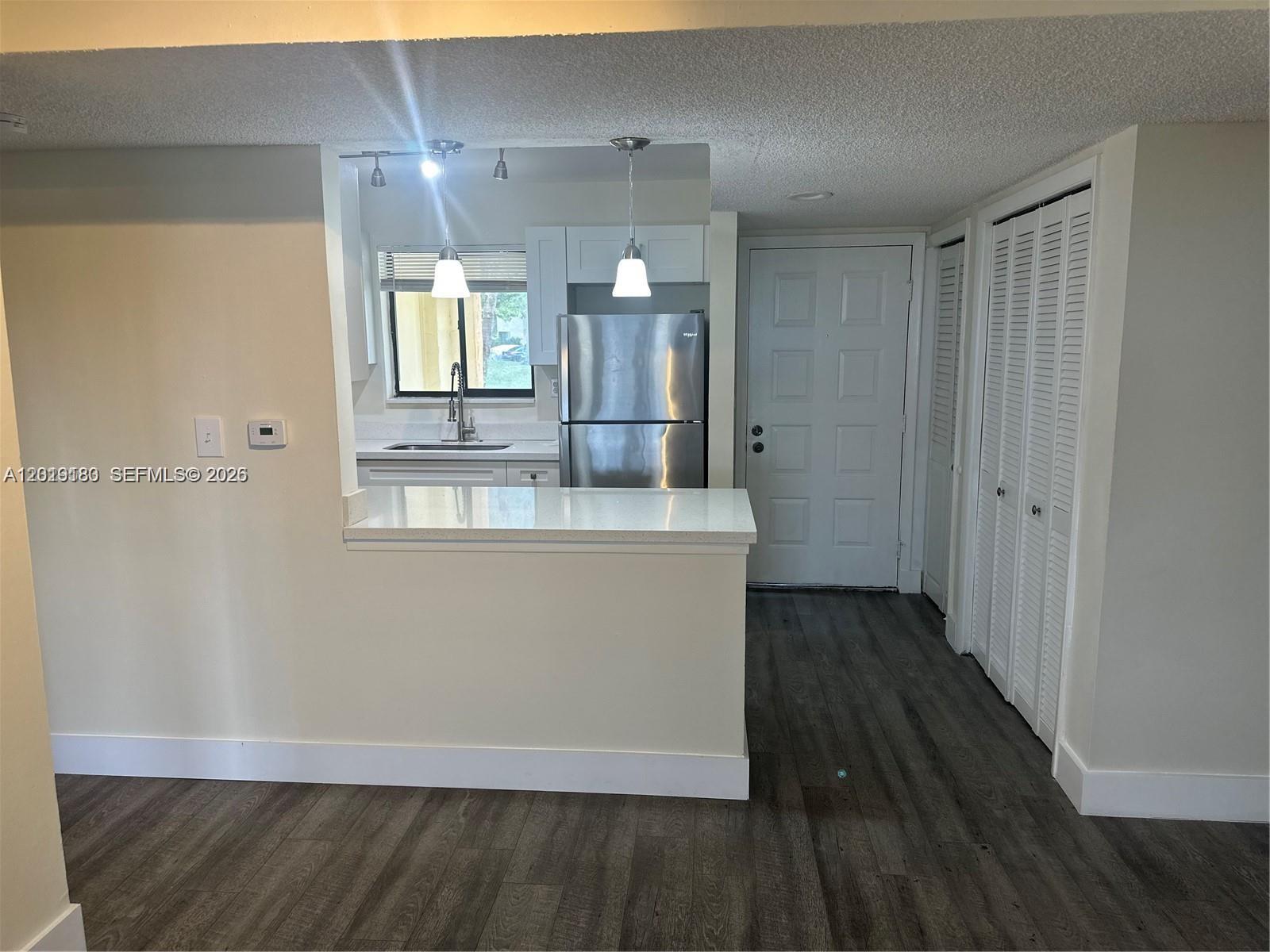A kitchen with stainless steel appliances and a breakfast bar overlooks a living area — WESTON, FL