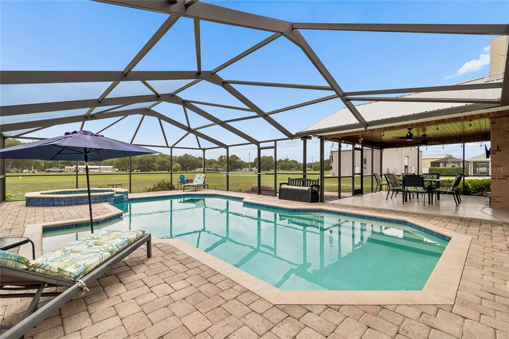 A screened-in patio features a swimming pool, a hot tub, and a covered dining area — 5150 SOUTHWIND DRIVE, MULBERRY, FL