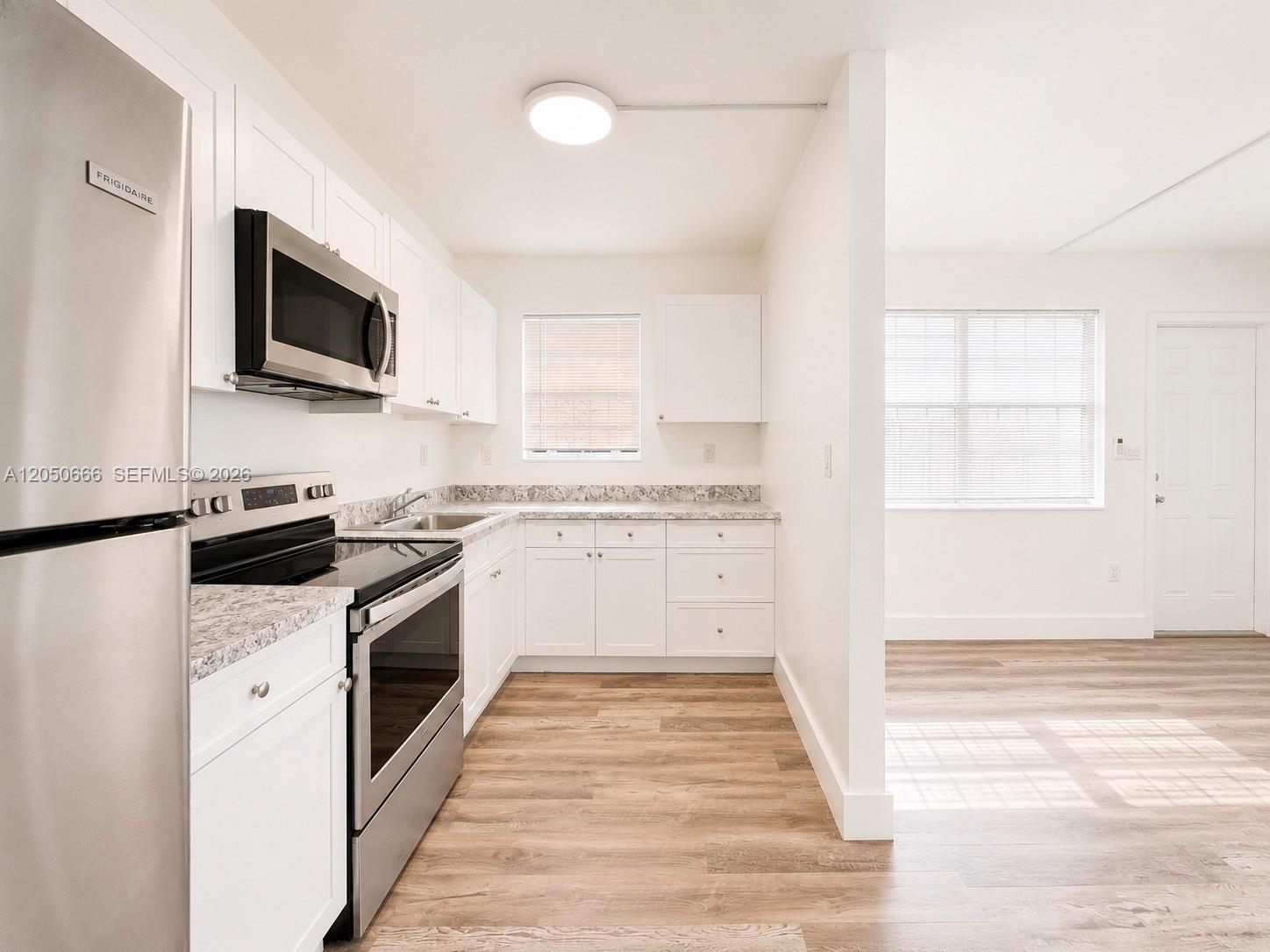 A kitchen with white cabinets, stainless steel appliances, and light wood-look flooring — 46 NW 62nd St # 4, Miami FL 33150, MIAMI, FL
