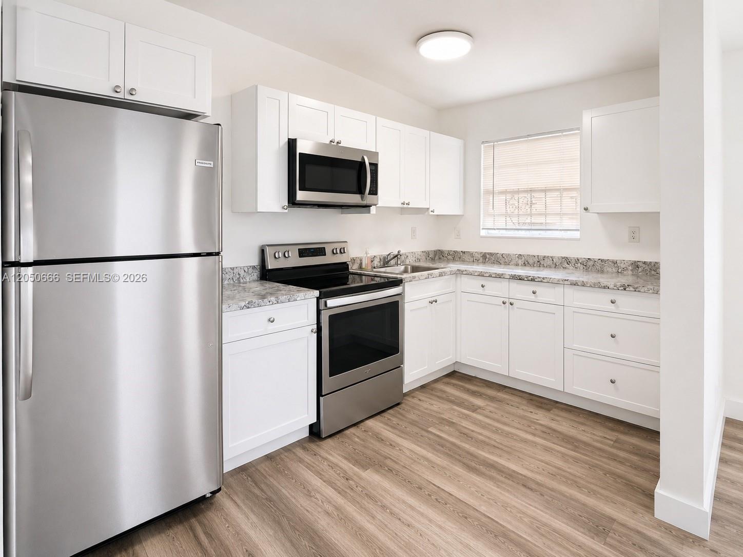 A kitchen features white cabinets, stainless steel appliances, granite countertops, and wood-look flooring — 46 NW 62nd St # 4, Miami FL 33150, MIAMI, FL