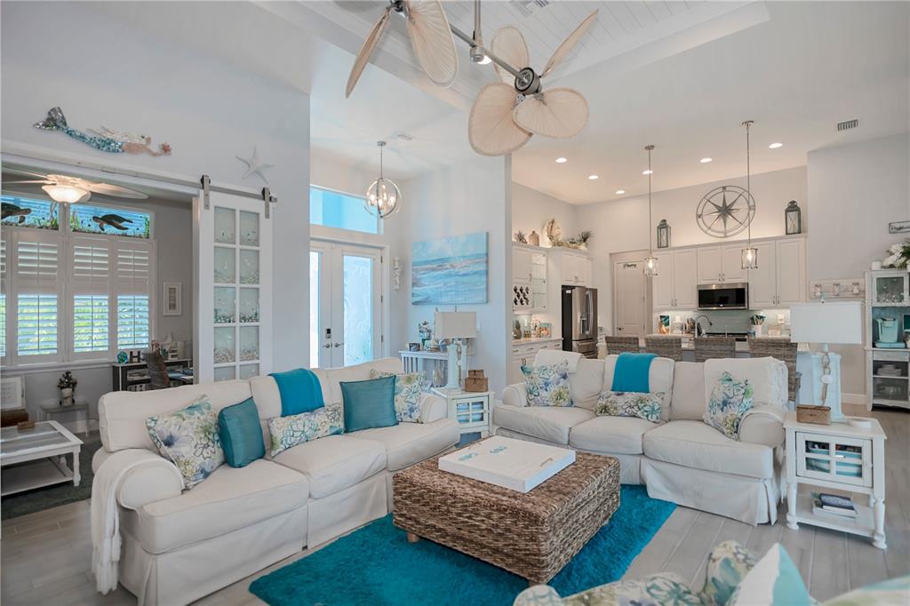 A coastal-style living room features white sofas, a woven ottoman, and a bright blue rug — 10136 AMY TERRACE, PORT CHARLOTTE, FL