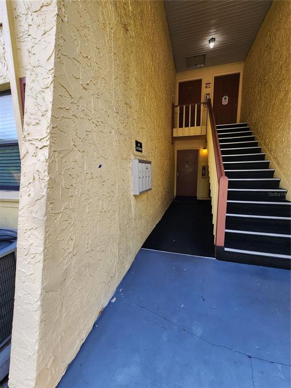 An outdoor stairwell leads to two apartment doors in a yellow stucco building — 7597 ABONADO ROAD UNIT 7597, TAMPA, FL