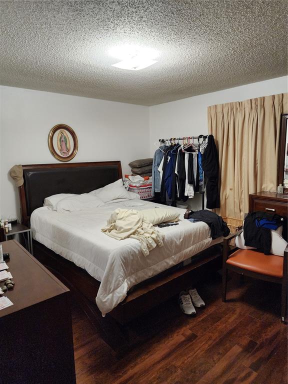 A bedroom features a dark wood bed frame, a clothing rack, and wood-look flooring — 7597 ABONADO ROAD UNIT 7597, TAMPA, FL