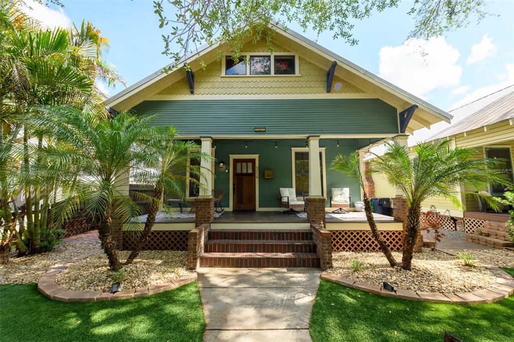 A green bungalow with a front porch, brick steps, and palm trees in the yard — 314 E FRANCES AVENUE, TAMPA, FL
