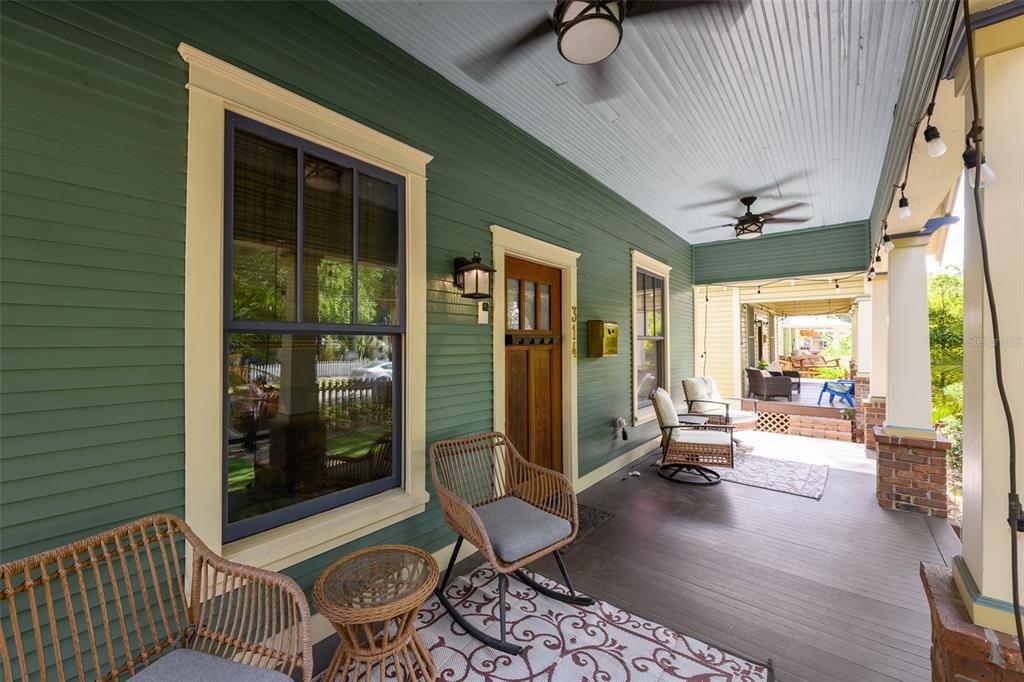 A covered front porch features green siding, a wooden door, and wicker seating furniture — 314 E FRANCES AVENUE, TAMPA, FL