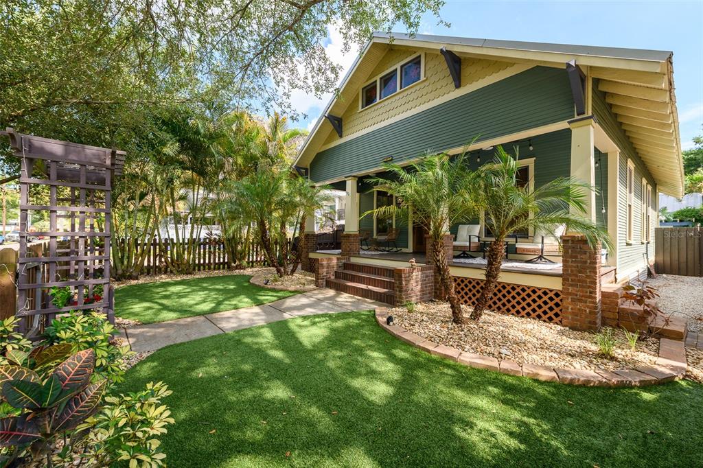 A green bungalow with a front porch, brick pillars, and a landscaped artificial turf yard — 314 E FRANCES AVENUE, TAMPA, FL