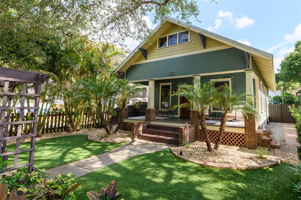 A green bungalow with a front porch, brick columns, and a manicured lawn — 314 E FRANCES AVENUE, TAMPA, FL