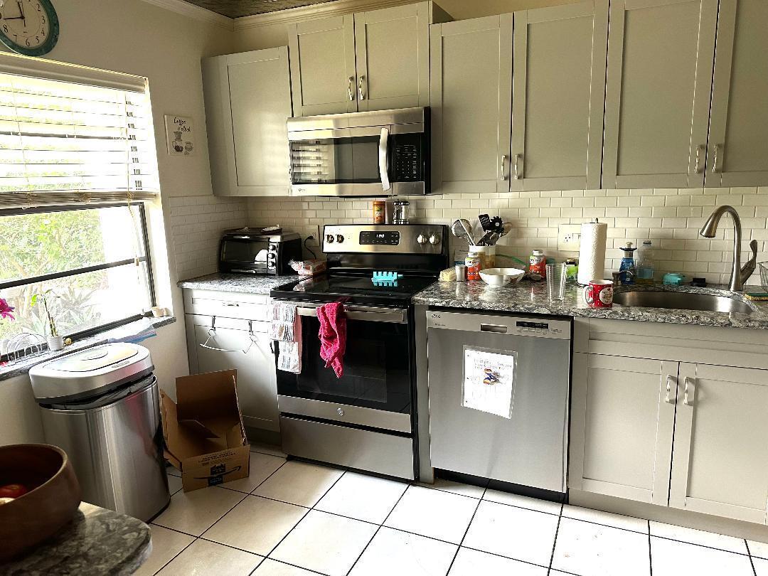 A kitchen features grey cabinets, stainless steel appliances, a tiled backsplash, and a window — 21848 Arriba Real # A, Boca Raton FL 33433, BOCA RATON, FL