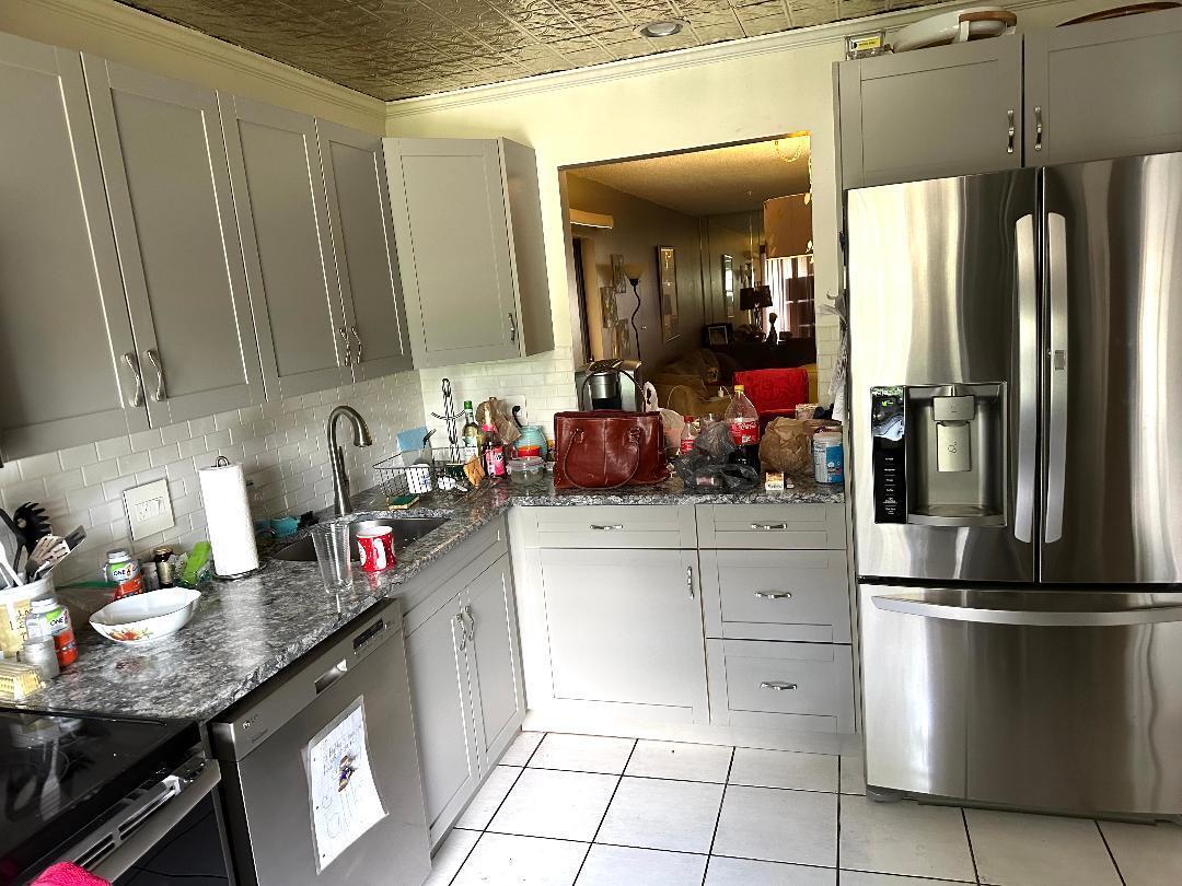 A kitchen features gray cabinets, granite countertops, stainless steel appliances, and a patterned tin ceiling — 21848 Arriba Real # A, Boca Raton FL 33433, BOCA RATON, FL
