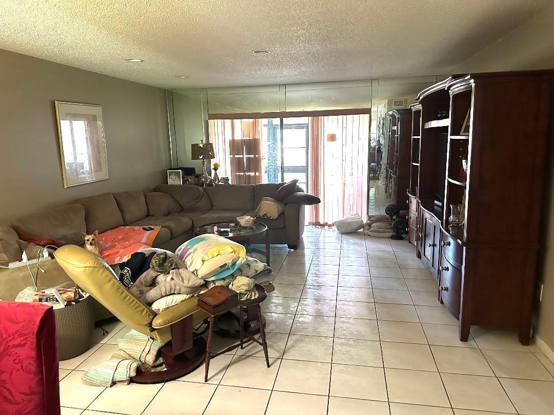 A living room features a large sectional sofa, a wooden entertainment center, and tiled flooring — 21848 Arriba Real # A, Boca Raton FL 33433, BOCA RATON, FL