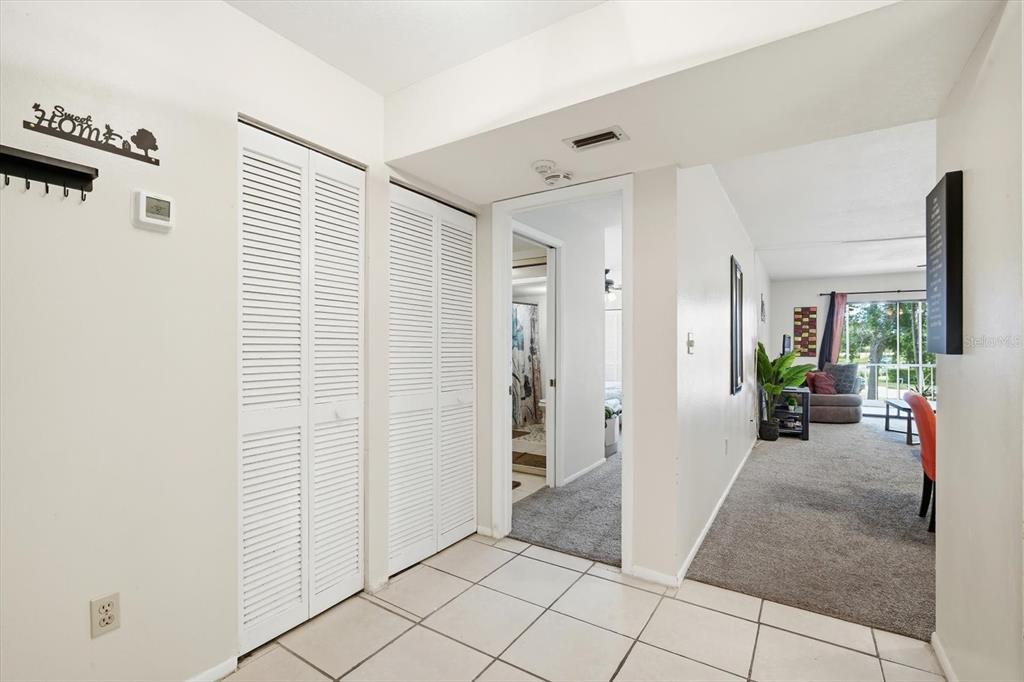 A tiled entryway leads to a carpeted hallway and living area with white louvered closet doors — 7500 40TH AVENUE W UNIT 203, BRADENTON, FL