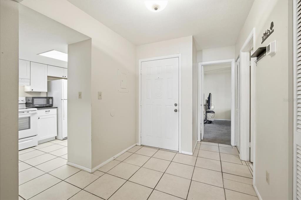 A tiled entryway leads to a white kitchen and a doorway into another room — 7500 40TH AVENUE W UNIT 203, BRADENTON, FL