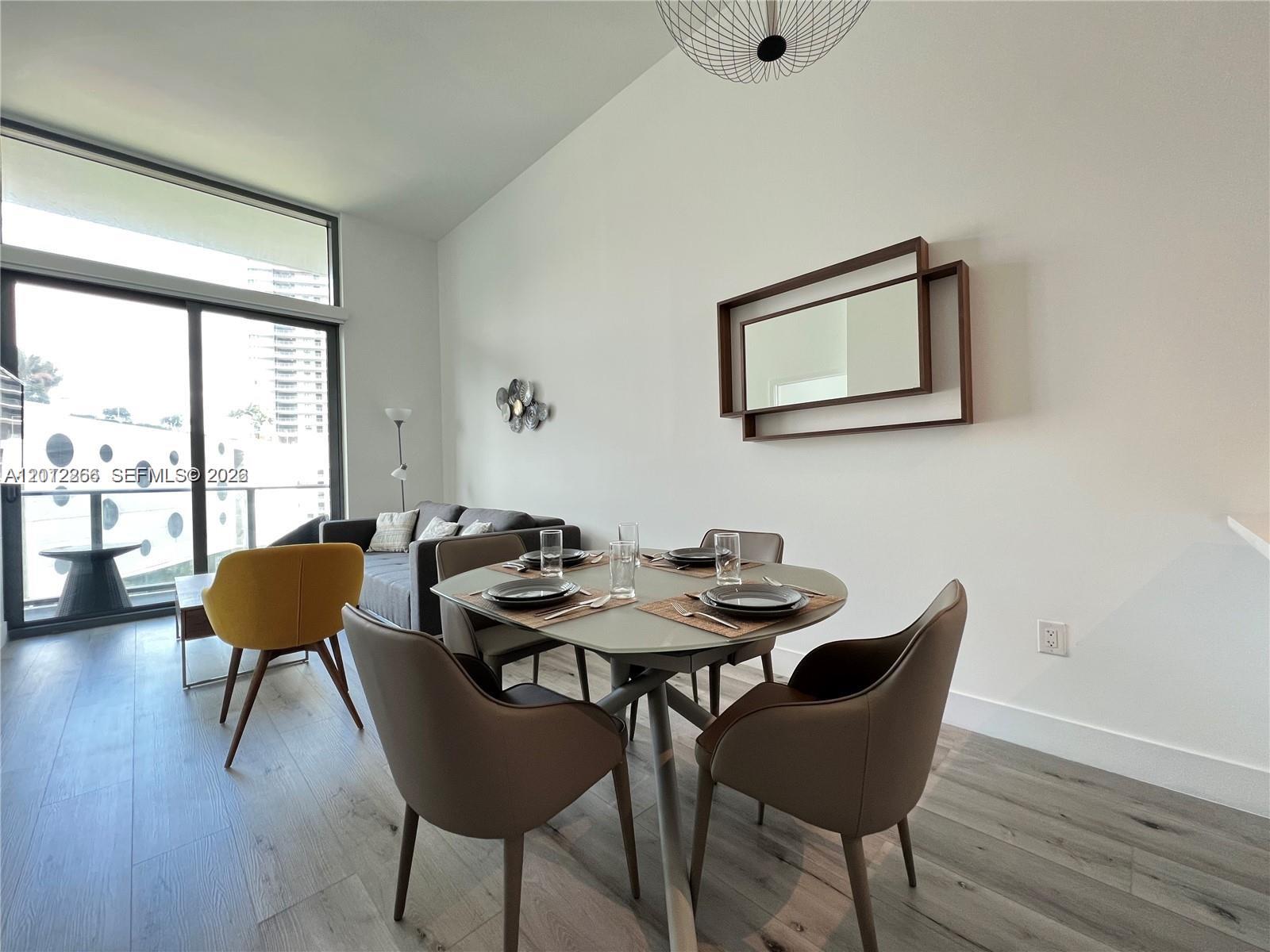 A dining area with a round table and chairs sits next to a living space — 501 NE 31st St # 404, Miami FL 33137, MIAMI, FL