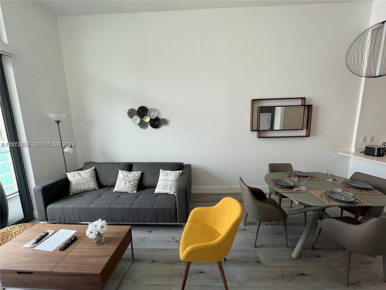 A living and dining area features a gray sofa, yellow chair, and round dining table — 501 NE 31st St # 404, Miami FL 33137, MIAMI, FL