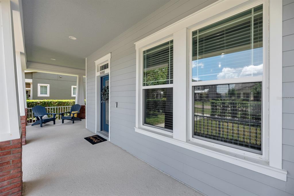 A covered front porch features gray siding, a blue front door, and two blue chairs — 14103 BARRINGTON STOWERS DRIVE, LITHIA, FL