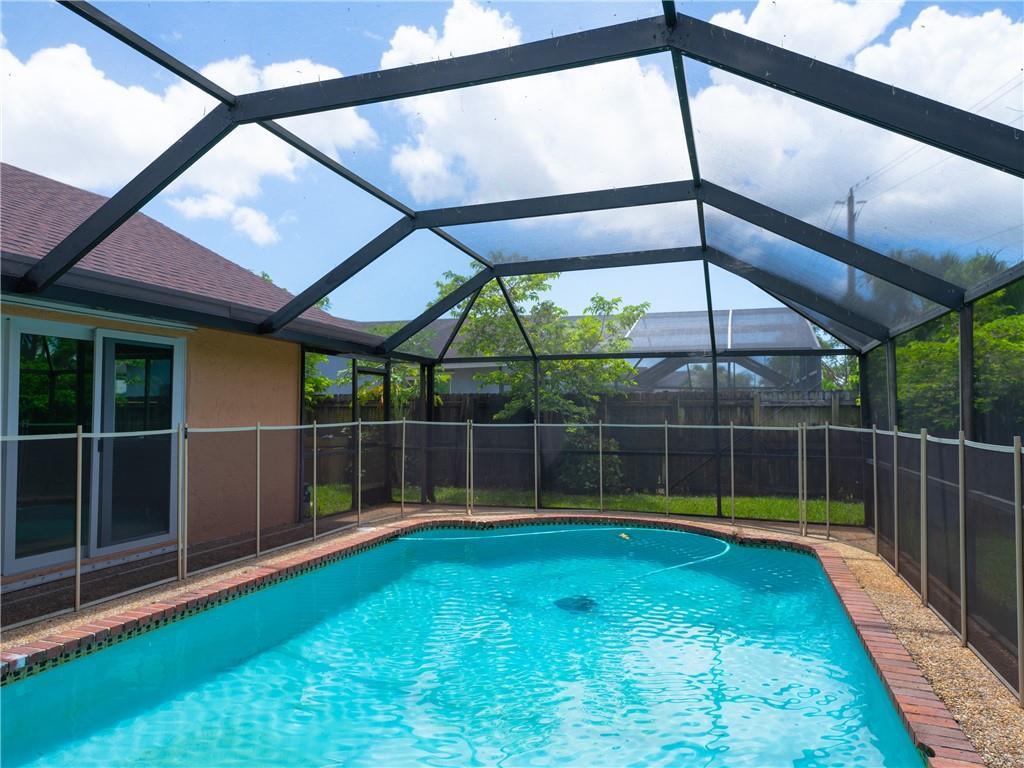 A swimming pool enclosed by a screened lanai and a safety fence in a backyard — 5332 NW 29th Court, Margate FL 33063, MARGATE, FL