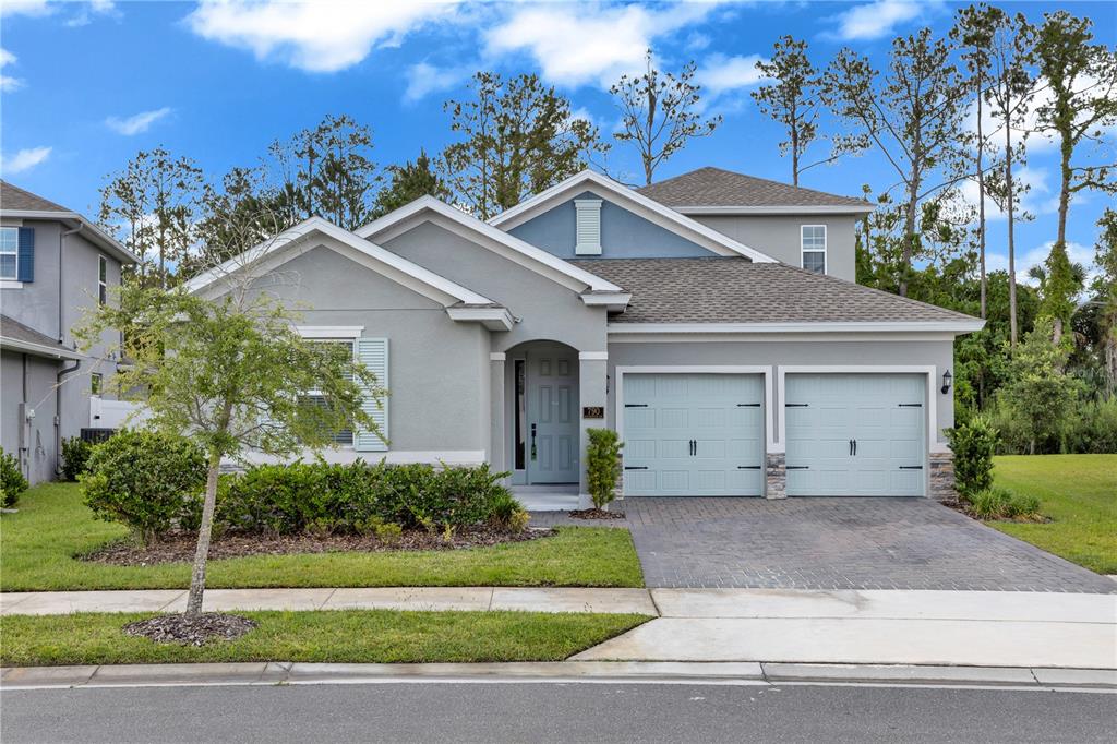 A two-story suburban house features a gray stucco exterior, two garage doors, and a driveway — 790 HYPERION DRIVE, DEBARY, FL