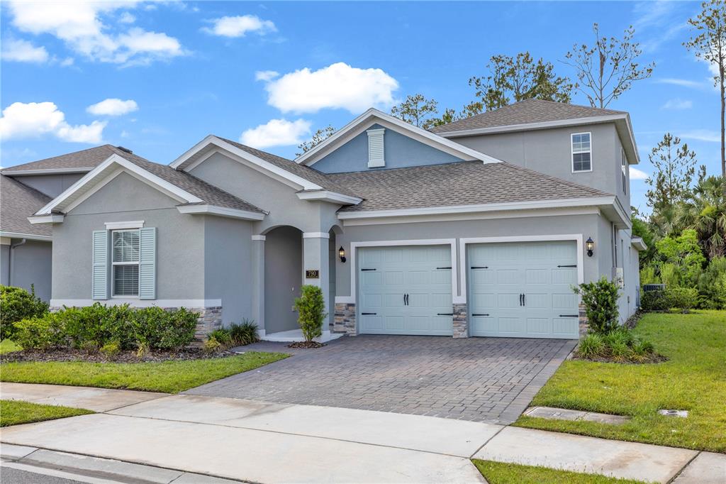 A two-story suburban house features a gray stucco exterior, a two-car garage, and stone accents — 790 HYPERION DRIVE, DEBARY, FL