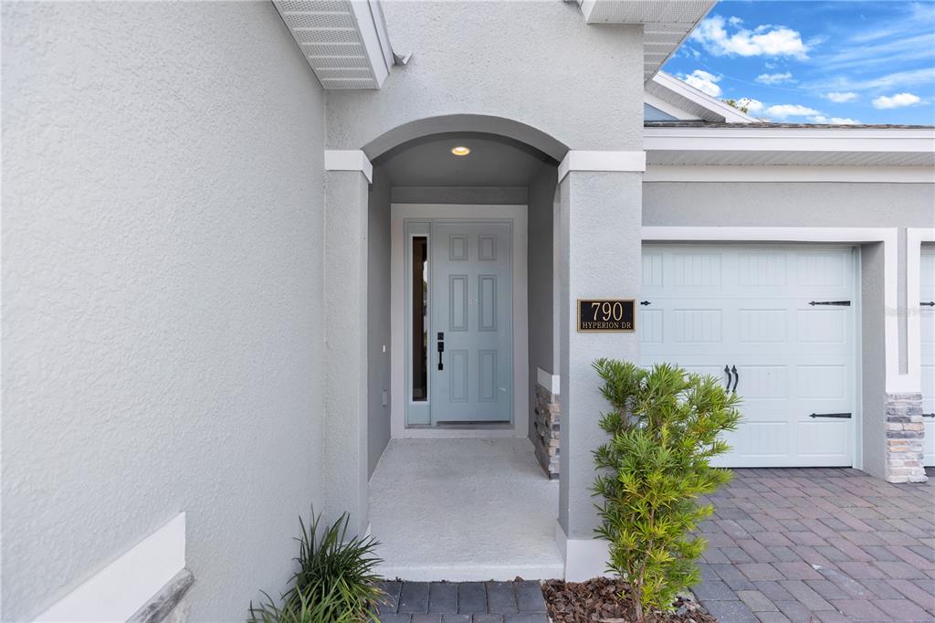 The exterior of a house features a light blue front door, a garage, and stone accents — 790 HYPERION DRIVE, DEBARY, FL