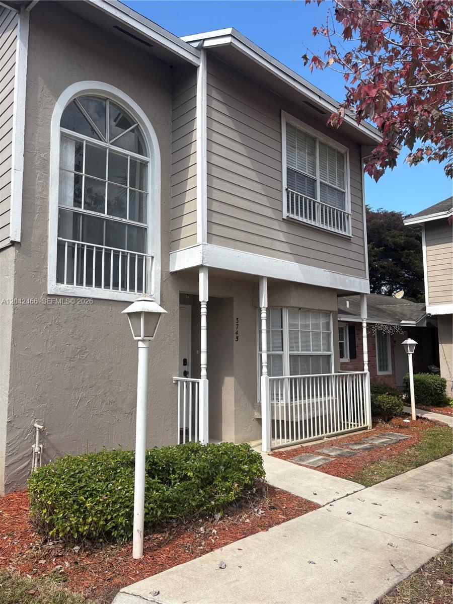 A two-story house exterior features tan siding, a covered porch, and an arched window — 3743 NW 122nd Ter, Sunrise FL 33323, SUNRISE, FL