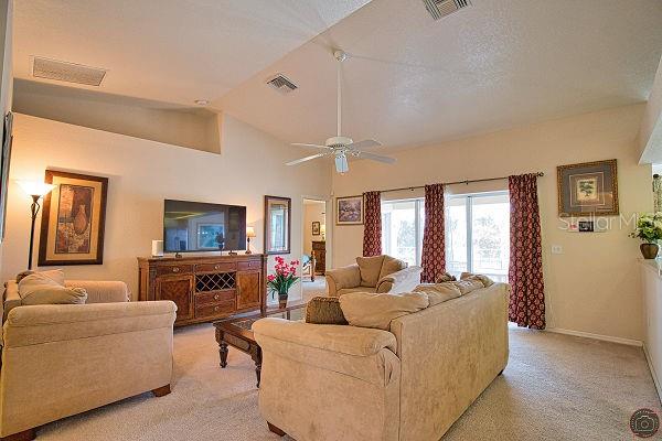 A living room features beige carpet, a ceiling fan, a television console, and upholstered furniture — 116 ALBATROSS ROAD, ROTONDA WEST, FL