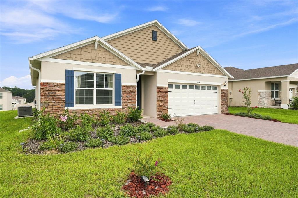 A single-story suburban house with a stone facade, tan siding, and a two-car garage — 33464 COPPER HILL WAY, SORRENTO, FL