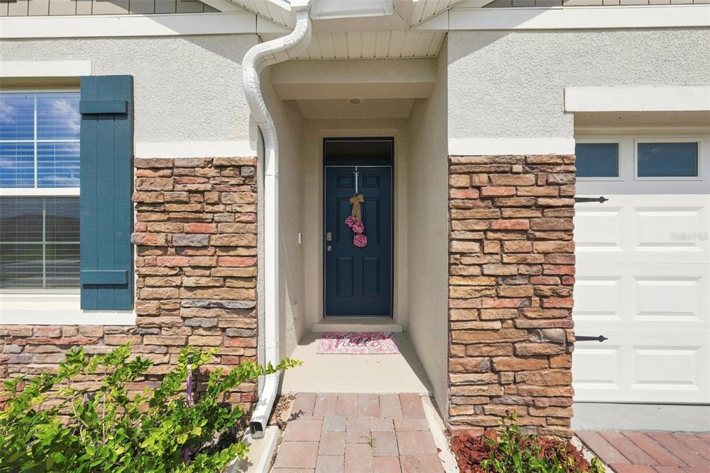 The exterior of a home features a blue front door, stone veneer, and a walkway — 33464 COPPER HILL WAY, SORRENTO, FL