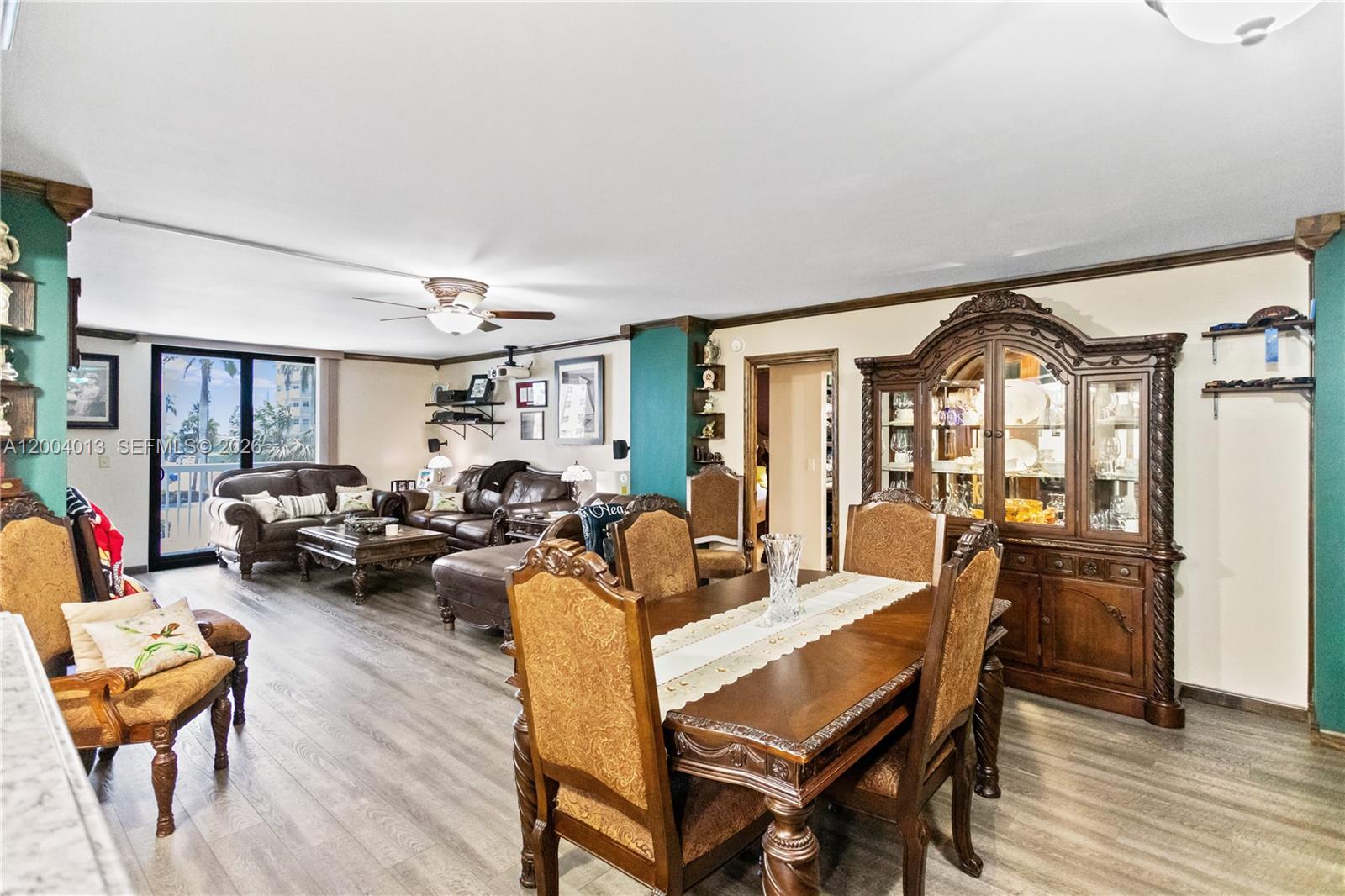 A dining area and living room feature wood-look flooring, teal accent walls, and traditional furniture — 1500 S Ocean Dr # 2G, Hollywood FL 33019, HOLLYWOOD, FL