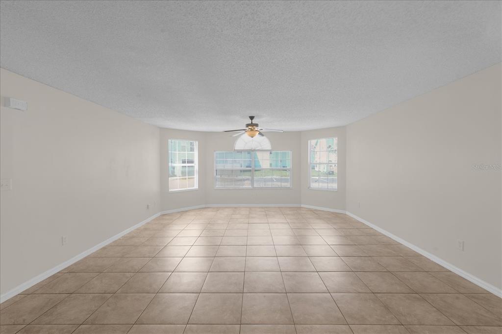 An empty room with beige tile flooring, light-colored walls, and a ceiling fan — 2731 N POINCIANA BOULEVARD UNIT 107, KISSIMMEE, FL