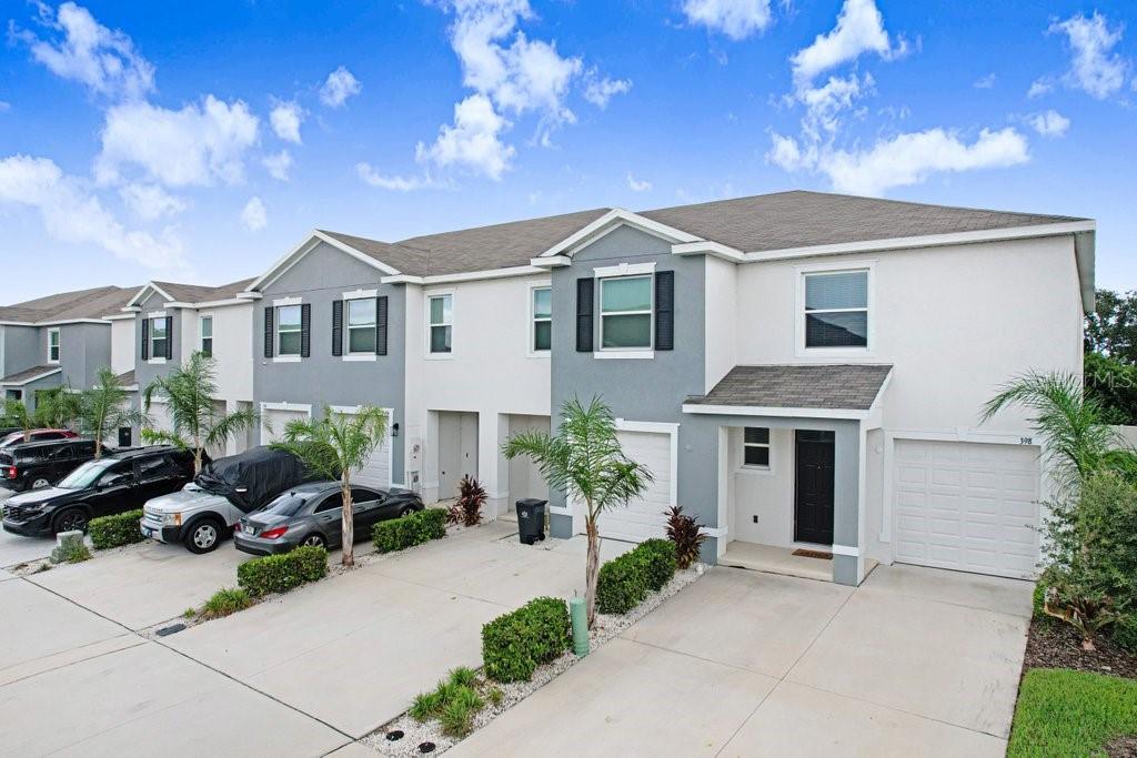 A row of two-story townhomes with gray and white siding, attached garages, and concrete driveways — 398 MANGROVE SHADE CIRCLE, APOLLO BEACH, FL