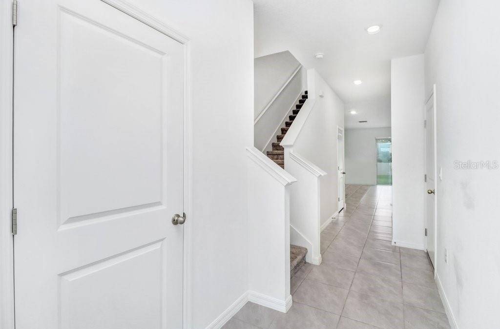A bright entryway features white walls, tile flooring, and a staircase with carpeted steps — 398 MANGROVE SHADE CIRCLE, APOLLO BEACH, FL