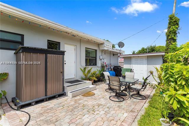 A paved patio features a metal storage shed, a dining set, and a small detached building — 2407 Dewey St, Hollywood FL 33020, HOLLYWOOD, FL