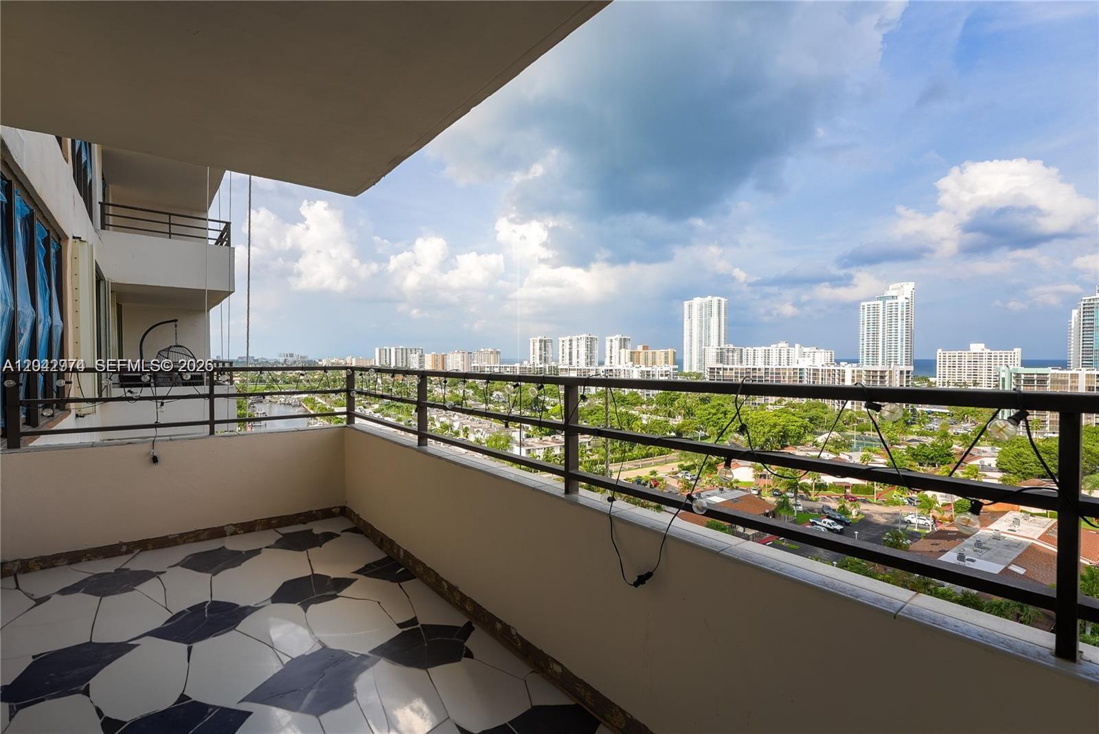 A balcony with patterned tile flooring overlooks a city skyline and a residential area — 2500 Parkview Dr # 1503, Hallandale Beach FL 33009, HALLANDALE BEACH, FL