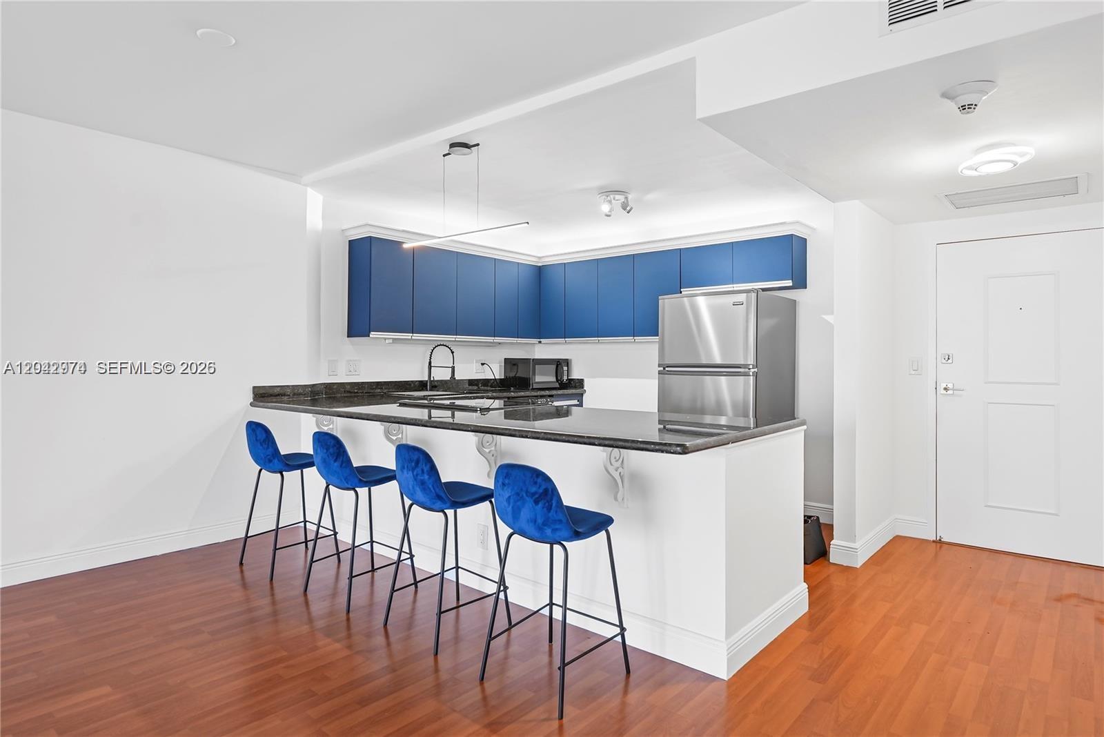 A kitchen features blue upper cabinets, a dark countertop, and four blue bar stools — 2500 Parkview Dr # 1503, Hallandale Beach FL 33009, HALLANDALE BEACH, FL